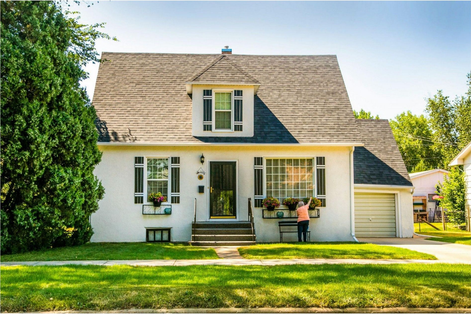 A white house with a gray roof and green lawn